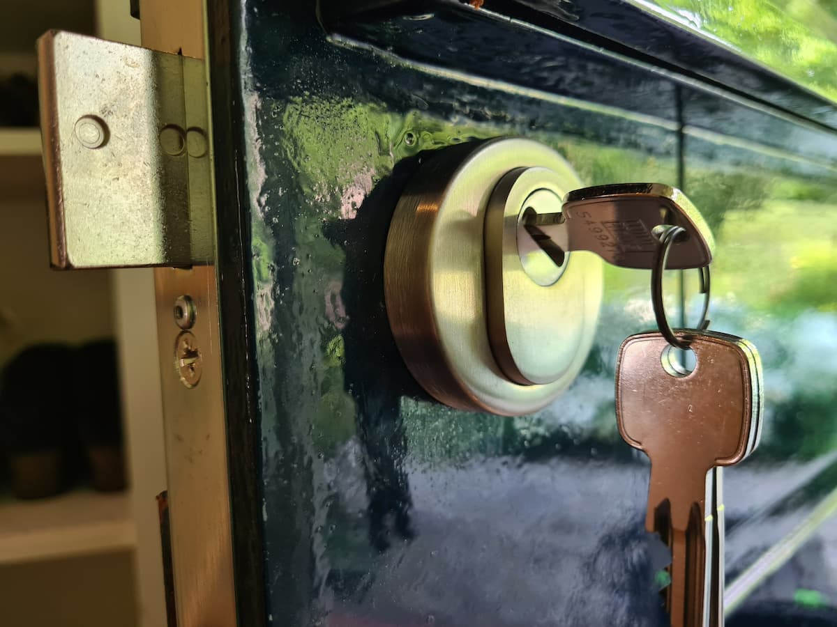 Detailopname van een modern deurslot met kerntrekbeveiliging en een sleutel in de cilinder, volgens de eisen van het Politiekeurmerk Veilig Wonen.