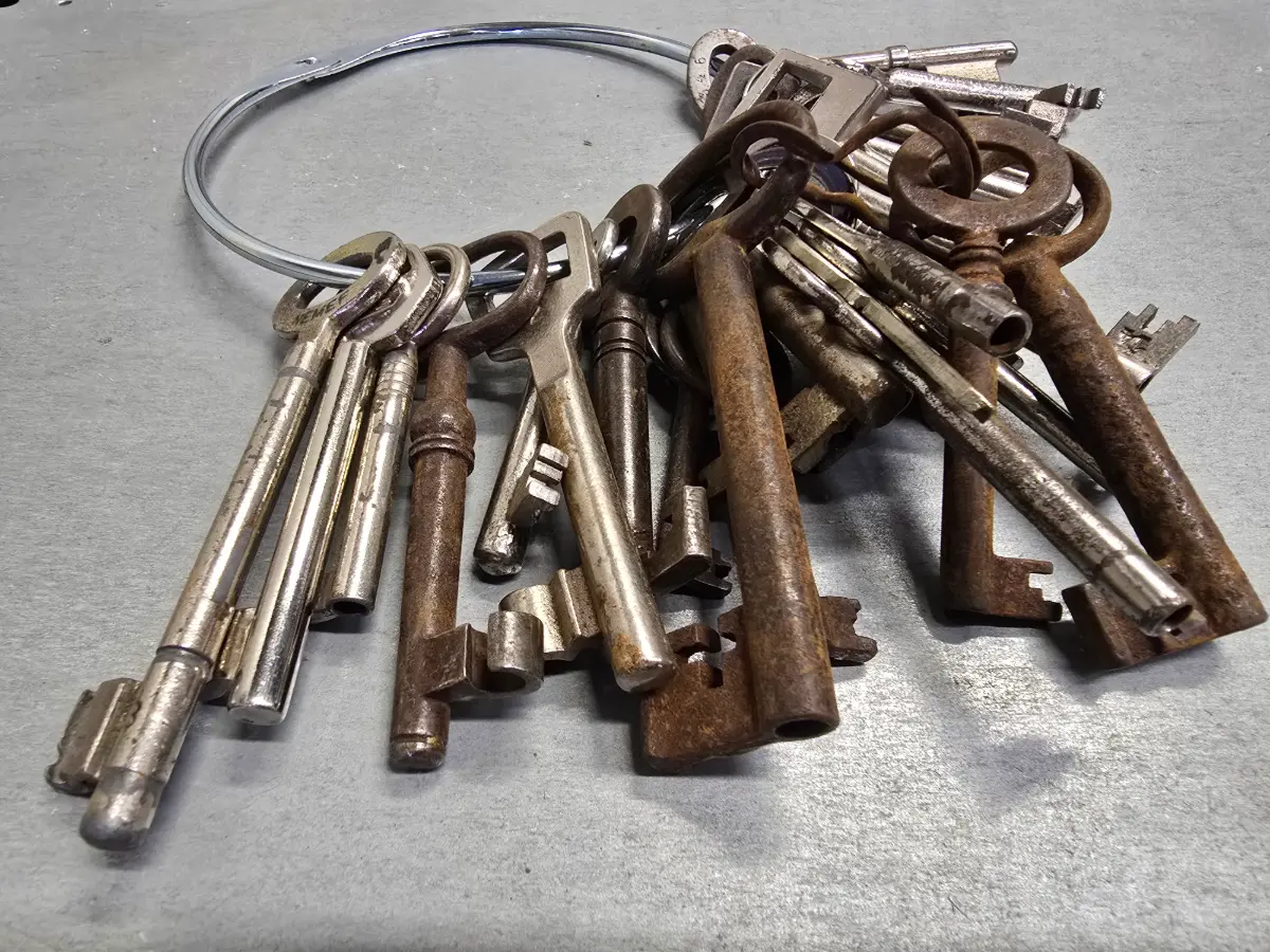 Een ongeorganiseerde verzameling van veel oude, verroeste loopsleutels aan een grote ring, wat de noodzaak voor een modern en gestructureerd sleutelplan benadrukt.